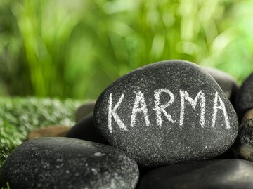Stein mit Schrift "Karma" | © Getty Images/Liudmila Chernetska