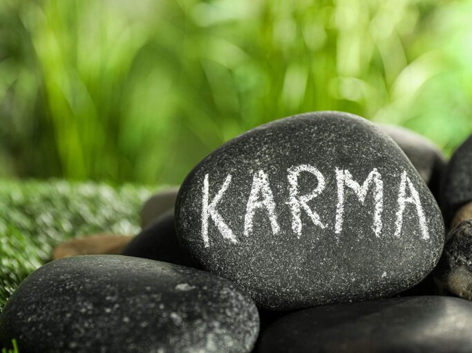 Stein mit Schrift "Karma" | © Getty Images/Liudmila Chernetska