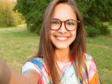 Junge Frau mit Brille macht im Park ein Selfie. | © Adobe Stock / litts