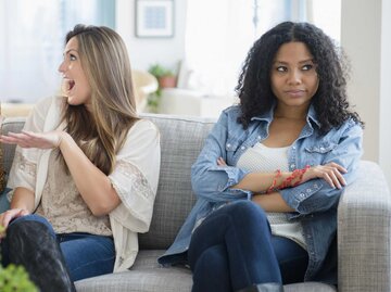 Zwei Frauen unterhalten sich, während eine dritte Frau mürrisch guckt | © Getty Images/JGI/Jamie Grill