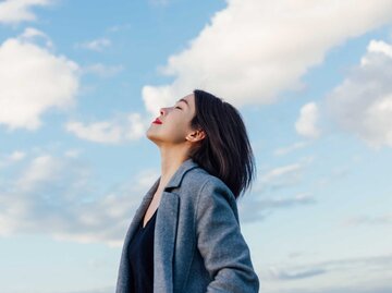 Junge Frau genießt blauen Himmel mit geschlossenen Augen | © Getty Images/Oscar Wong