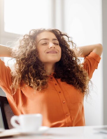 Junge Frau in orangem Pullover macht Pause vor dem Laptop | © AdobeStock/Prostock-studio