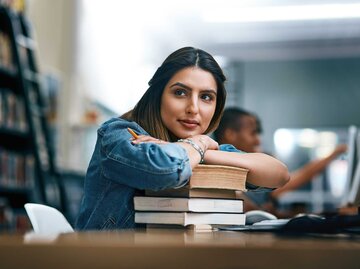 Schlaue Frau stützt sich auf Büchern ab | © Getty Images/PeopleImages