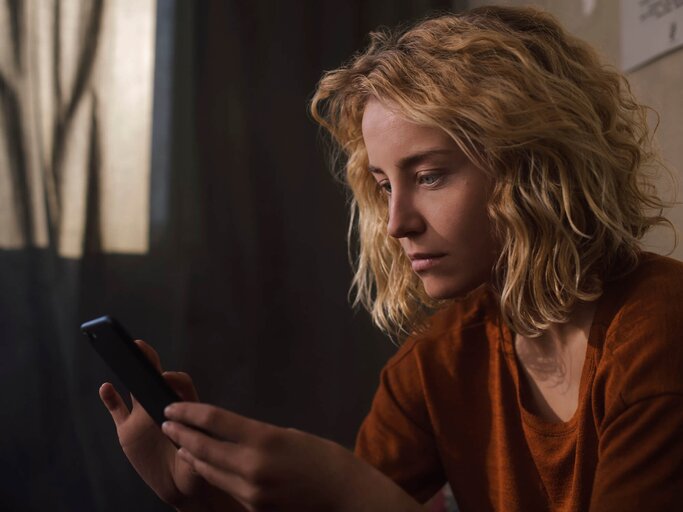 Frau blickt traurig auf ihr Handy | © Getty Images/Westend61