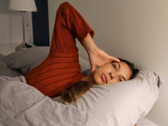 Frau liegt mit gestresster Miene im Bett | © IMAGO/YAY Images