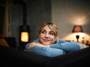 Frau sitzt gemütlich lächelnd auf dem Sofa | © Getty Images/Westend61