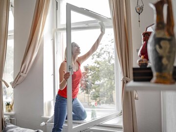 Frau putzt ein Fenster. | © Getty Images / Westend61