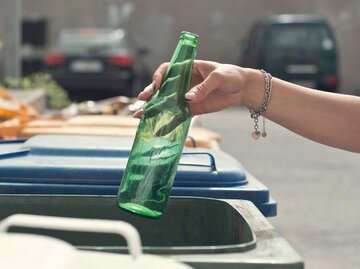 Frau wirft eine grüne Glasflasche in den Hausmüll. | © Getty Images / Francesco Carta fotografo