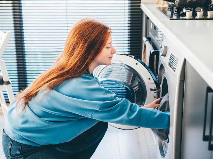 Junge Frau gefüllt die Waschmaschine | © Getty Images/Maria Korneeva
