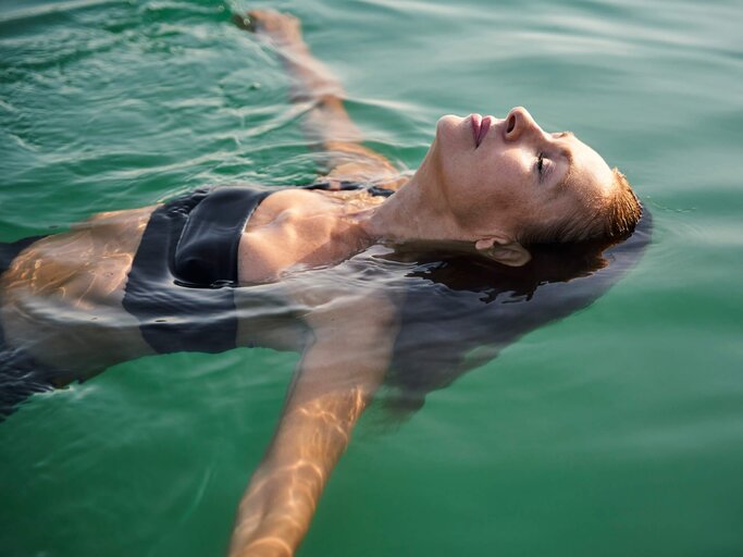 Frau liegt entspannt im Wasser  | © Getty Images/Westend61