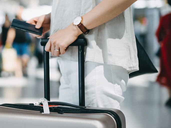 Frau steht mit ihrem Koffer am Flughafen | © Getty Images/d3sign