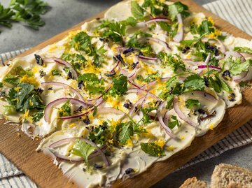Ein Brett mit Butter, roten Zwiebeln und frischen Kräutern | © Getty Images/bhofack2