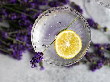 Ein Glas mit klarem Cocktail, einer Scheibe Zitrone und einem Stängel Lavendel | © Getty Images/annabogush