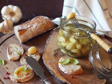 Ein Glas mit eingelegtem Knoblauch und geröstetes Brot mit Knoblauch bestrichen | © Getty Images/photosimysia