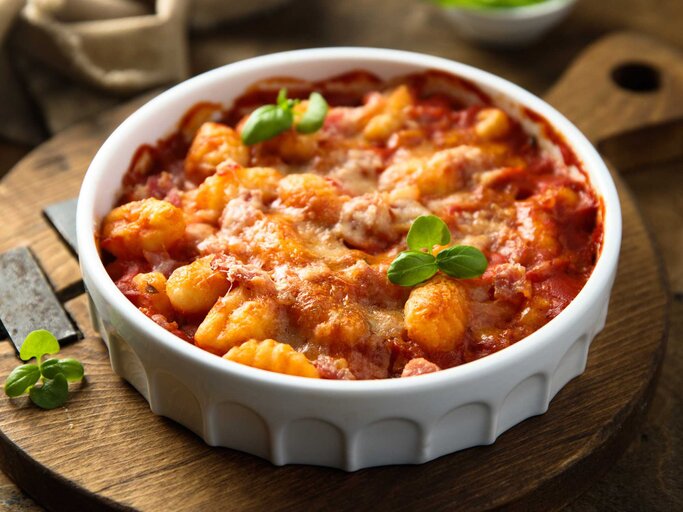 Ofenkartoffelgnocchi mit Tomatensauce und Basilikum auf einem Holztisch mit etwas  frischem Basilikum garniert | © Getty Images/Mariha-kitchen