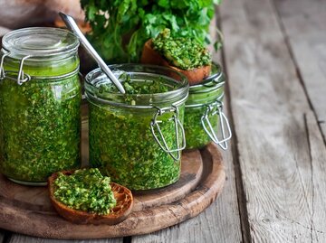 Koriander-Pesto in Gläsern und auf einer Scheibe Brot. | © Getty Images / Karaidel