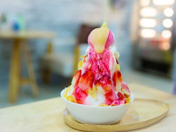 Ein Eis aus geriebenen Früchten in einer Schale, mit frischen Erdbeeren garniert, seitliche Aufnahme | © Getty Images/kckate16