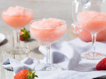 Gläser mit einem pinken Granita stehen auf dem Tisch, daneben liegen Erdbeeren.  | © Getty Images / bhofack2
