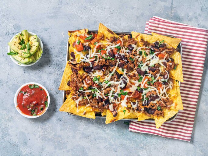 Ein Teller überbackende Nachos mit zwei separaten Soßen | © Getty Images/Carlo A