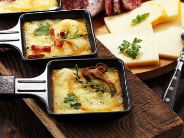 Nahaufnahme von drei Raclette Pfännchen auf einem Tisch | © Adobe Stock/beats_