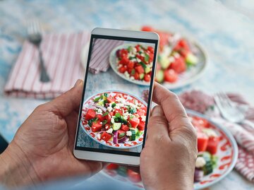 Frau macht mit ihrem Handy ein Foto von einem Wassermelonen-Feta-Salat | © Getty Images/GMVozd