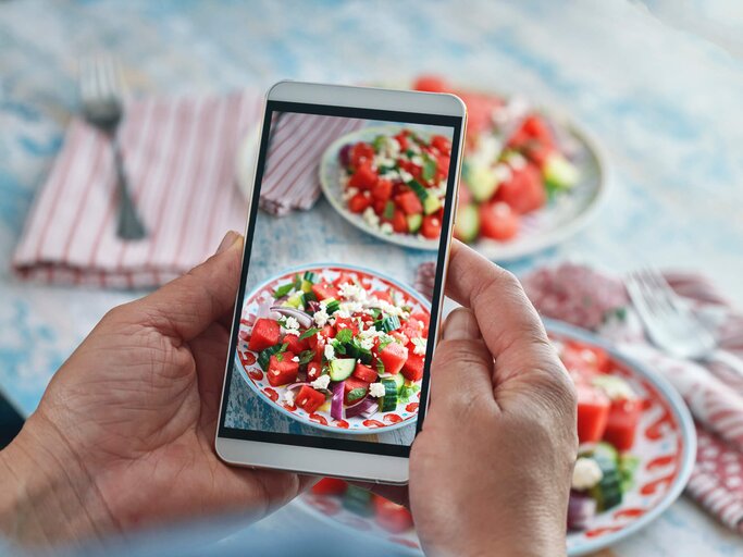 Frau macht mit ihrem Handy ein Foto von einem Wassermelonen-Feta-Salat | © Getty Images/GMVozd