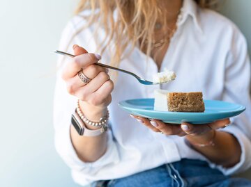 Frau hat Teller mit einem Stück Käsekuchen in der Hand | © Getty Images/Alexey Dulin / EyeEm