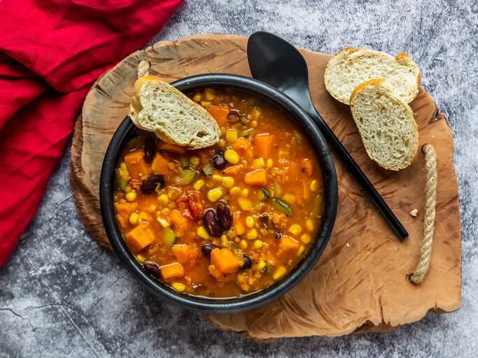 Chili con Kürbis mit Baguette serviert | © Getty Images/lacaosa