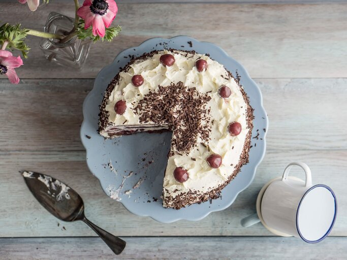 Falsche Schwarzwälder Kirschtorte angeschnitten und auf blauer Kuchenplatter serviert | © Getty Images/Westend61