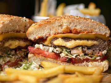 Aufgeschnittener Cheeseburger mit Pommes | © Getty Images/Artur Kozlov