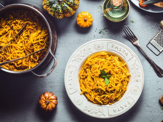 Spaghetti mit Kürbis in Teller und Topf | © Getty Images/VICUSCHKA