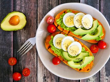 Nahaufnahme von einem Süßkartoffel Toast mit Guacamole, Avocadostücken, gekochtem Ei und Tomaten | © Getty Images/jenifoto