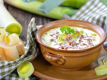 Käse-Lauch-Suppe mit Hackfleisch in einem braunen Ton-Teller. | © Getty Images / kabVisio