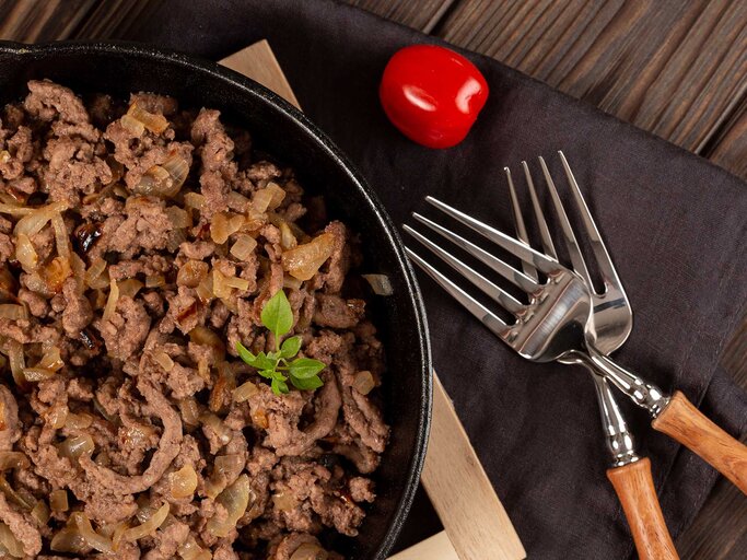 Hackfleisch gebraten mit Zwiebeln und Gewürzen in einer gusseisernen Pfanne. | © Getty Images/Natalya Ugryumova