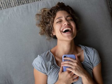lachende Frau mit Handy in der Hand | © Getty Images/andresr