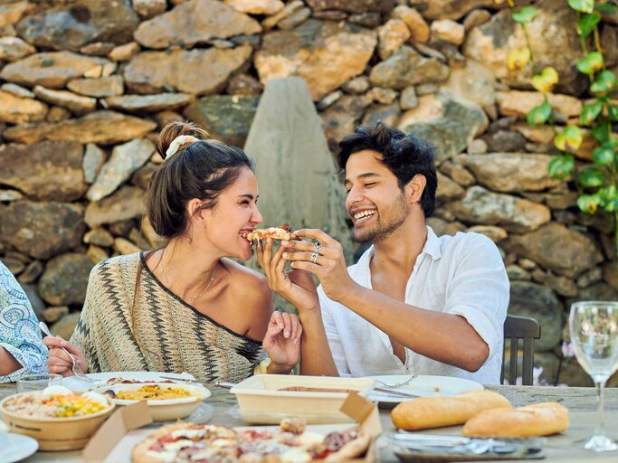 Junges, gut aussehendes Paar füttert sich mit Pizza und lacht | © Imago/Addictive Stock