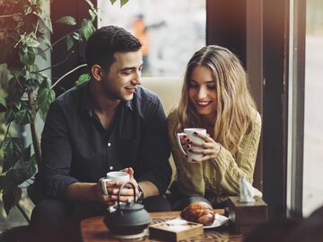 Junges Paar sitzt bei einem Date im Café und trinkt Kaffee und isst Kuchen. | © Getty Images / ArthurHidden