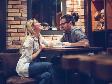Frau und Mann sitzen bei einem Date in einem Café und lachen. | © Adobe Stock/zorandim75