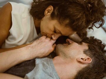 Junges Paar liegt im Bett und küsst sich | © Getty Images/Maskot