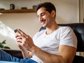 Mann schreibt SMS und lächelt | © Getty Images/Luis Alvarez