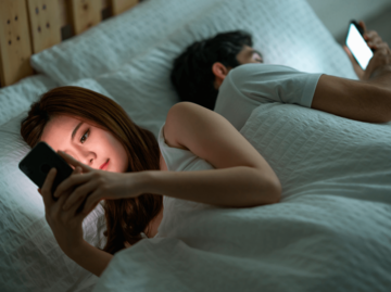Frau und Mann im Bett am Handy | © Getty Images/Cravetiger