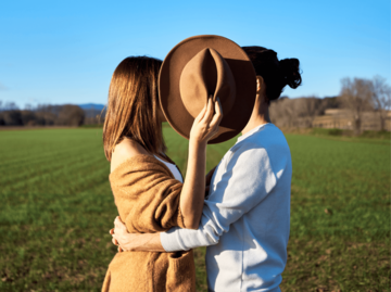 Frau und Mann verstecken sich hinter Hut | © Getty Images/Westend61