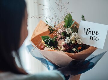 Frau erhält Blumenstrauß mit Karte "I love yu" | © Getty Images/Oscar Wong