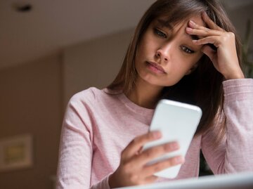 Frau blickt traurig auf ihr Handy | © Getty Images/JGI/Jamie Grill