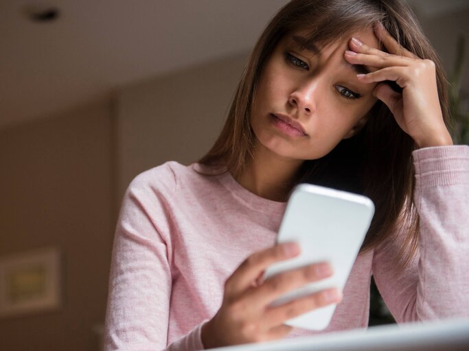 Frau blickt traurig auf ihr Handy | © Getty Images/JGI/Jamie Grill