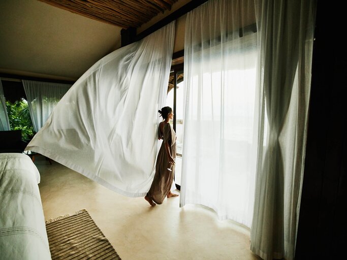 Frau sieht aus dem Fenster | © Getty Images/Thomas Barwick