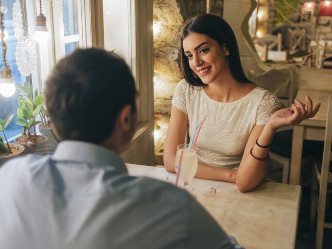 Frau und Mann sitzen zusammen in einem romantischen Restaurant | © Getty Images/Westend61