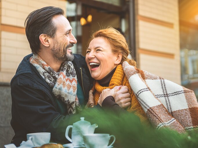 Mann & Frau sitzen vor einem Café und lachen. | © shutterstock/Olena Yakobchuk
