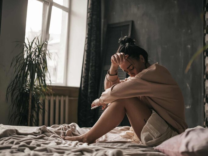 Frau sitzt traurig auf dem Bett | © Getty Images/Ol'ga Efimova / EyeEm