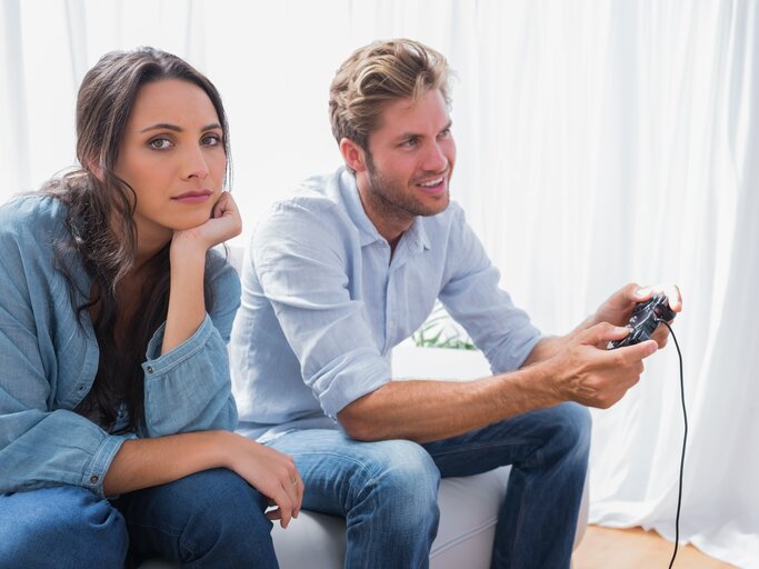 Frau ärgert sich, dass ihr Partner zu Hause auf dem Sofa Videospiele spielt | © shutterstock/wavebreakmedia